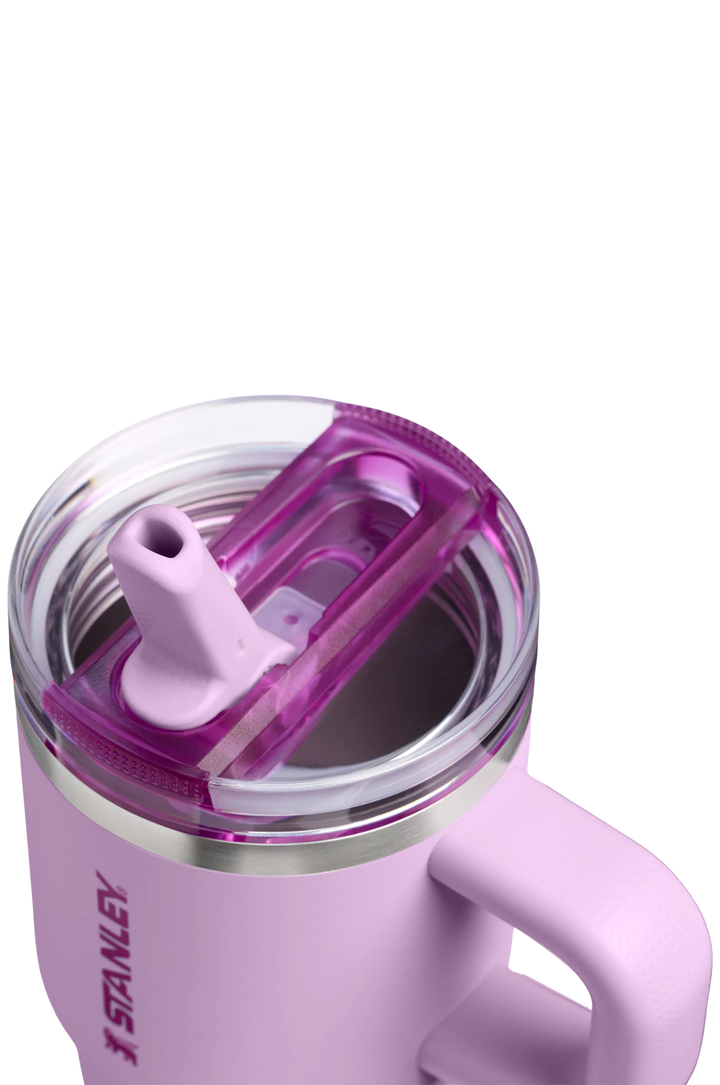 Close-up of a Stanley insulated tumbler in pastel pink with a translucent purple lid and clear rim, shown on a white background.#color_soft-orchid