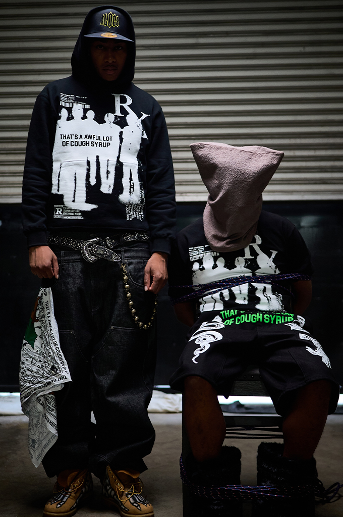A streetwear look featuring a black That's A Awful Lot Of Cough Syrup "Big Pharma" pullover graphic hoodie styled with matching oversized pants and a fitted cap.