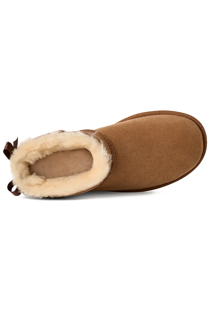 A single brown suede slipper boot with a cream-colored shearling lining, shown from a side profile view against a plain white background.