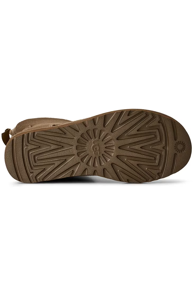 A close-up view of a brown boot sole, showing the tread pattern and a small embossed logo on the heel, set against a plain white background.#color_light-bronze