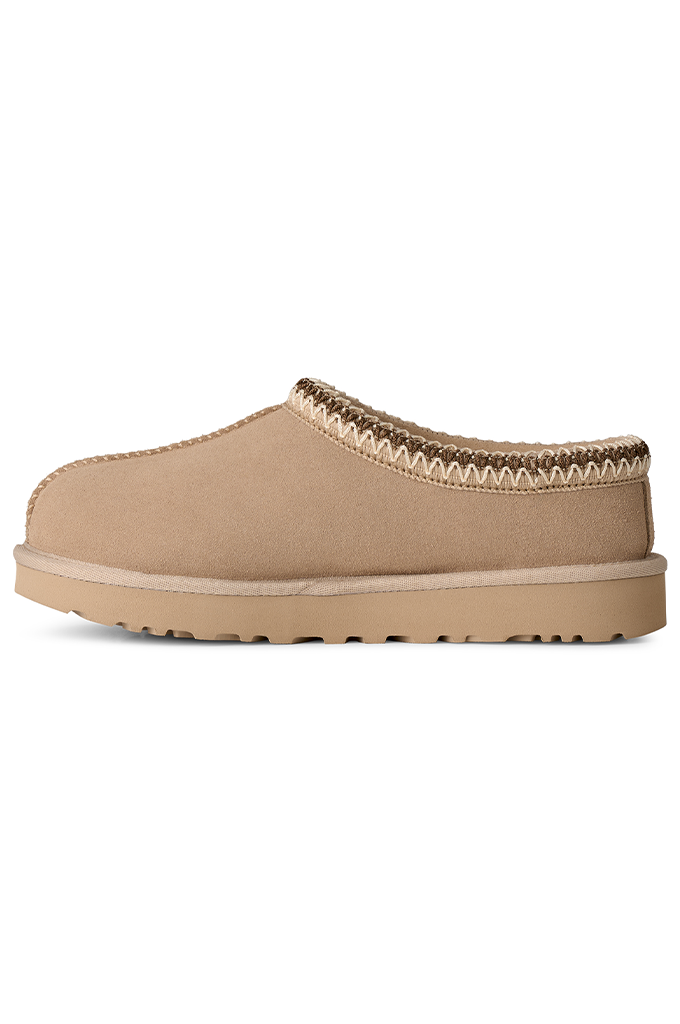A single beige slip-on clog-style shoe with a textured sole and decorative braided trim around the opening, shown against a plain white background.#color_moonlight