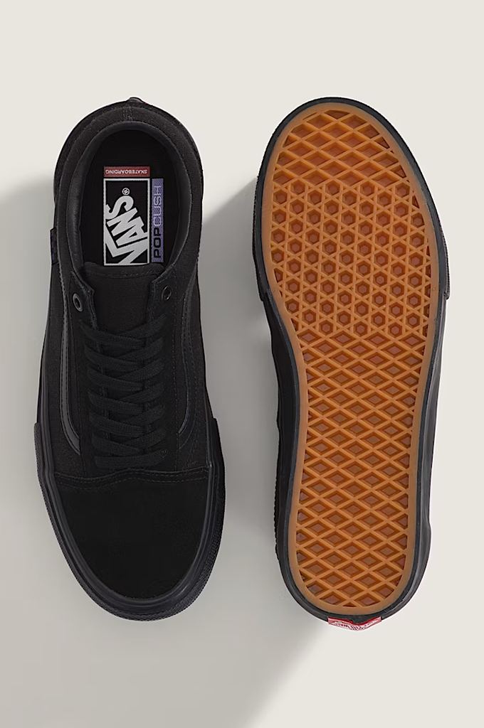 A pair of black Vans skate sneakers shown from a top-down view, displaying the black suede and canvas upper on one shoe and the brown waffle-patterned outsole on the other.