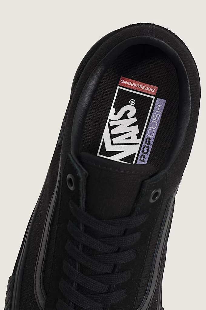 Close-up of a black Vans sneaker showing the inner side, laces, and the Vans logo on the tongue label.