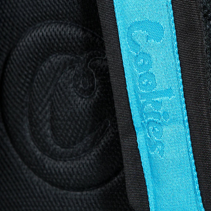 Close-up of black textured fabric with embossed logo and bright blue woven strap detail